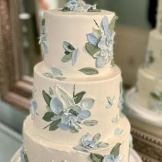 a three tiered white cake with blue flowers on it