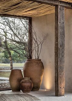 two large vases sitting under a wooden structure