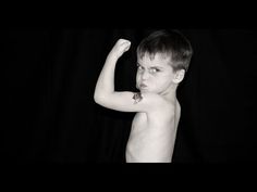 a shirtless young boy holding a tennis racquet