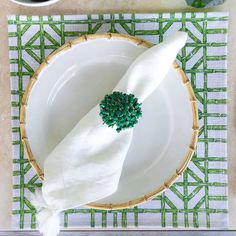 a white plate topped with a napkin and green leafy decoration on top of it