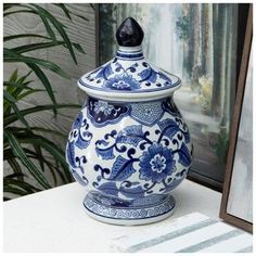 a blue and white vase sitting on top of a table next to a framed photo