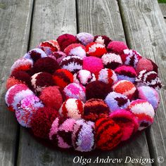 a bowl filled with lots of different colored balls on top of a wooden table next to grass