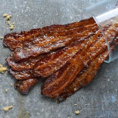 bacon is being poured into a container on top of the ground with salt and pepper