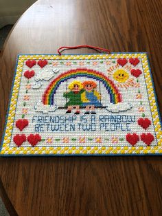 a wooden table topped with a cross stitched mat on top of a wooden table