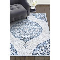 a blue and white area rug with an ornate design on the bottom, in front of a gray chair