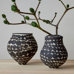 two black and white vases sitting next to each other on top of a table