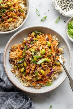 two bowls filled with rice and vegetables on top of a white countertop next to other dishes