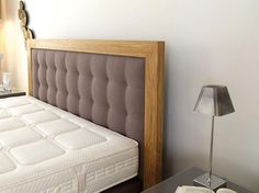 a bed with a wooden headboard next to a night stand and lamp in a bedroom