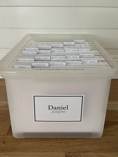 a plastic storage container filled with lots of name tags on the side of a wall