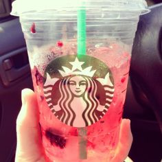 a person holding up a starbucks drink in their hand with ice and strawberries on it