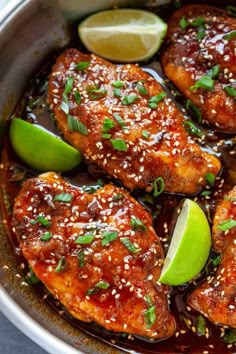 chicken with sesame seeds and limes in a skillet, ready to be eaten