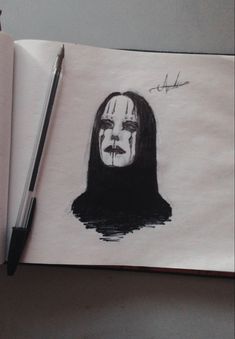 a drawing of a woman's face is shown on a notebook with a pen