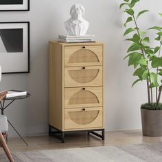 a white busturine on top of a wooden cabinet next to a potted plant