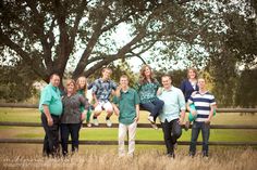 a group of people standing next to each other in front of a fence with trees