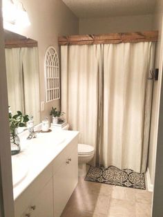 a bathroom with a sink, toilet and shower curtained in sheer curtains over the tub