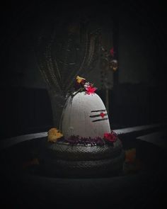 a white cake sitting on top of a table covered in flowers and leaves at night