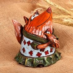 a ceramic figurine of a fox holding a fish on top of a piece of cloth