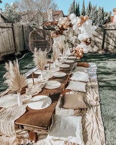 a long table is set up with balloons and place settings for an outdoor dinner party