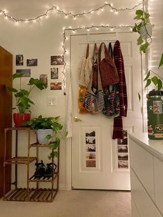 a white door with some plants and pictures on the wall next to it in a room