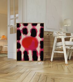 an abstract painting is displayed in the middle of a room with white chairs and wooden flooring