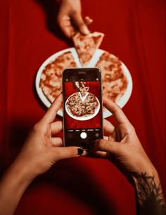 a person taking a photo of pizza on their phone