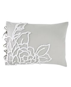 an embroidered pillow with white flowers on the front and grey linens on the back