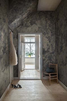 an open door leading into a room with wood flooring and wall paper on the walls