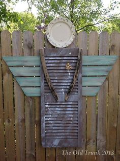 a wooden fence with a metal plate and wings on it