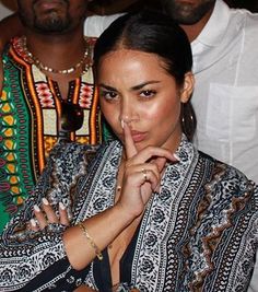 the woman is posing with her finger in her mouth and people behind her looking on