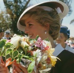 a woman in a hat is holding flowers