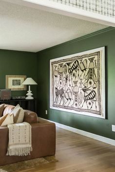 a living room with green walls and wood flooring in the center is a brown leather couch