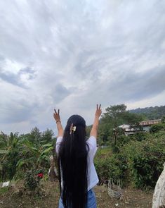 a woman with long black hair is flying a kite in the sky above her head