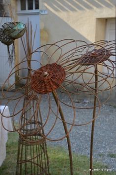 three metal sculptures in the shape of flowers on top of green grass and one is made out of wire