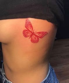 a woman's stomach with a red butterfly tattoo on her lower back and side