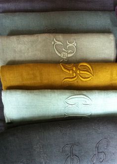 four towels are stacked on top of each other in different colors and designs, with the monogrammed symbols