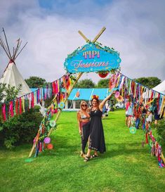 two women standing in front of a sign that says tipi famous on the grass