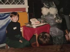 two children sitting in front of a table with a cake on it