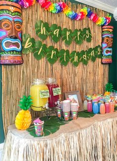 a table topped with lots of food next to a tiki mask wall hanging from the ceiling