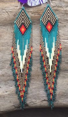 two pairs of beaded earrings hanging from a piece of wood