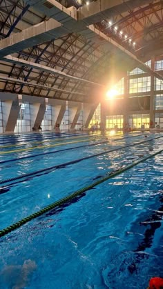 an indoor swimming pool with sun shining through the windows and water in it's surface