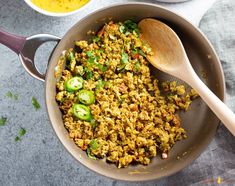 a pan filled with rice and vegetables next to a bowl of sauce on the side