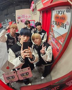 group of young men taking selfies in front of a mirror at an indoor event