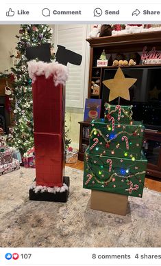 two cardboard christmas boxes sitting next to each other on top of a counter in front of a christmas tree