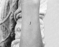 a woman's wrist with the word j on her left hand and an initial tattoo