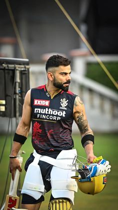 a man with tattoos holding a helmet and gloves