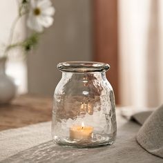 a glass jar with a candle inside on a table