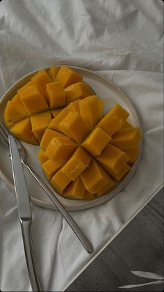 a plate with cut up mangoes on it next to silverware and utensils