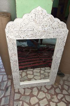 a white mirror sitting on top of a tiled floor