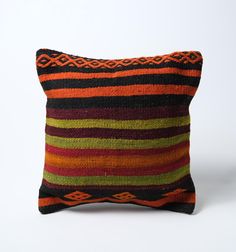 an orange, black and green striped pillow on a white background with the bottom half turned down