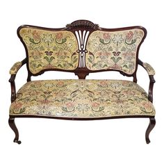 an ornate wooden bench with floral fabric upholstered on the armrests and back